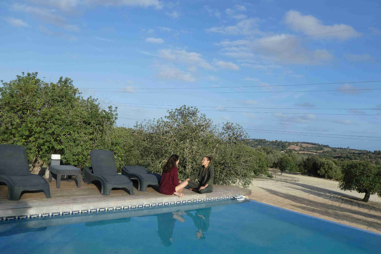 two people sitting outside near a pool talking in mallorca