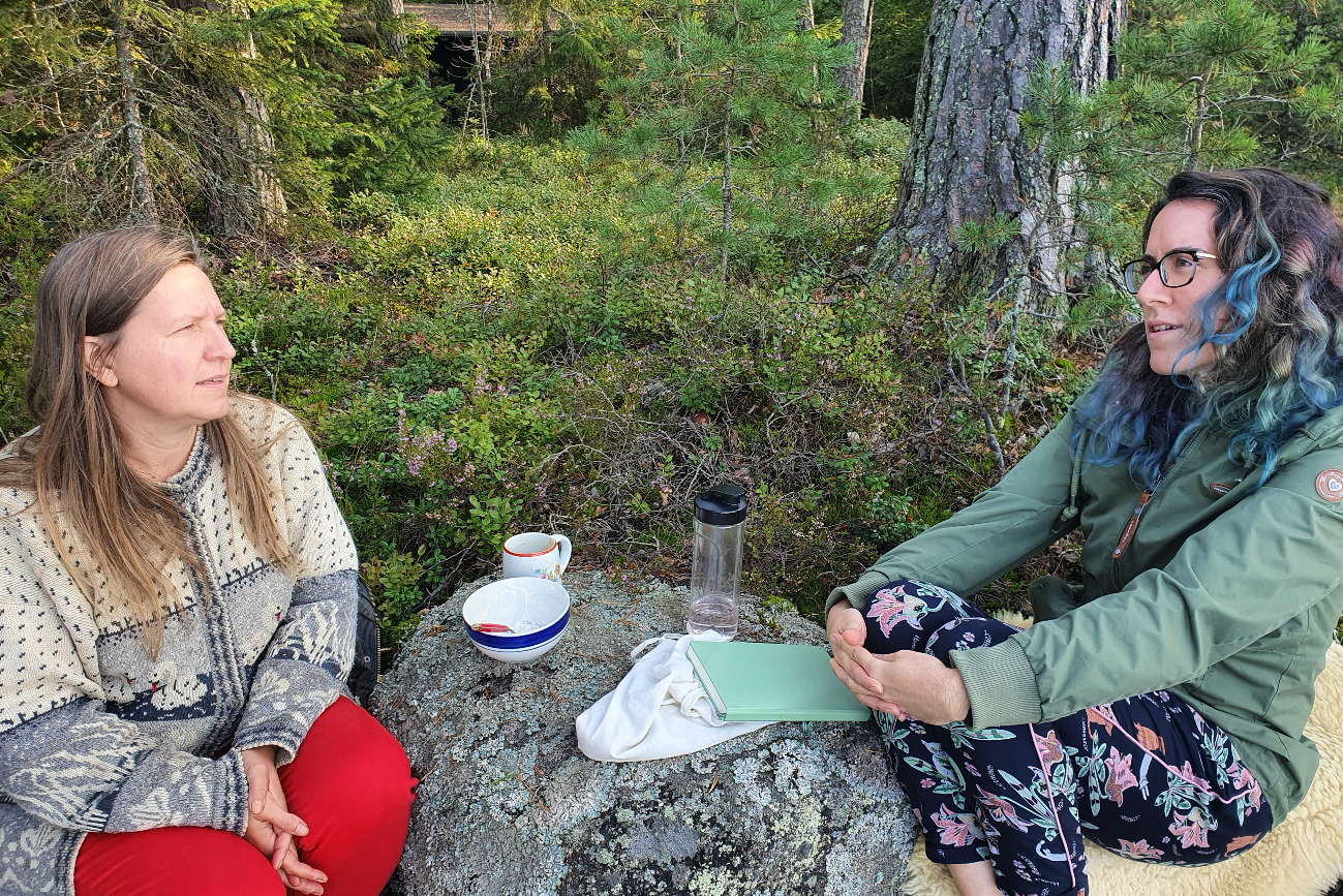 Two women sitting in the forest talking